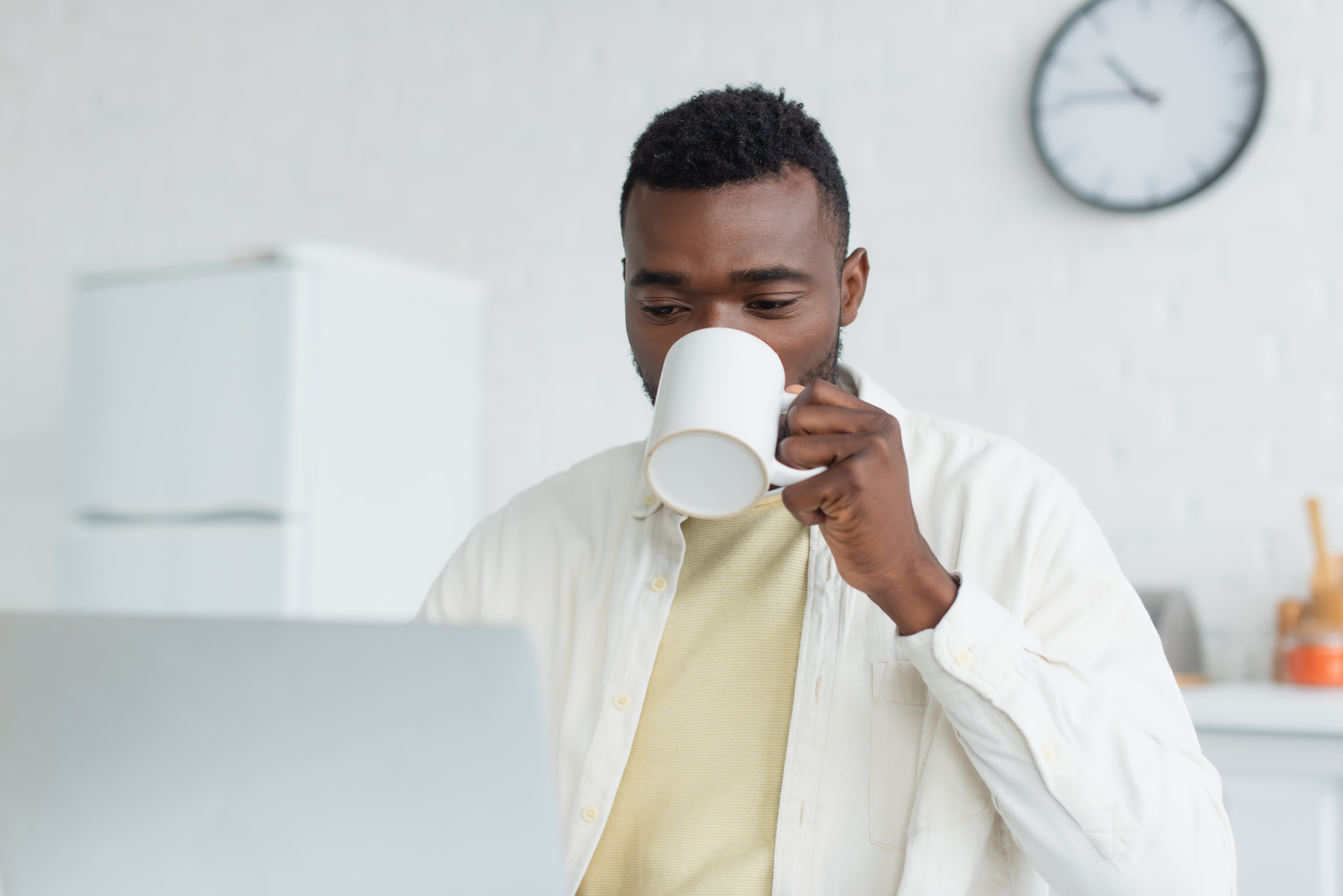 Un jeune africain buvant du cafe devant un pc portable